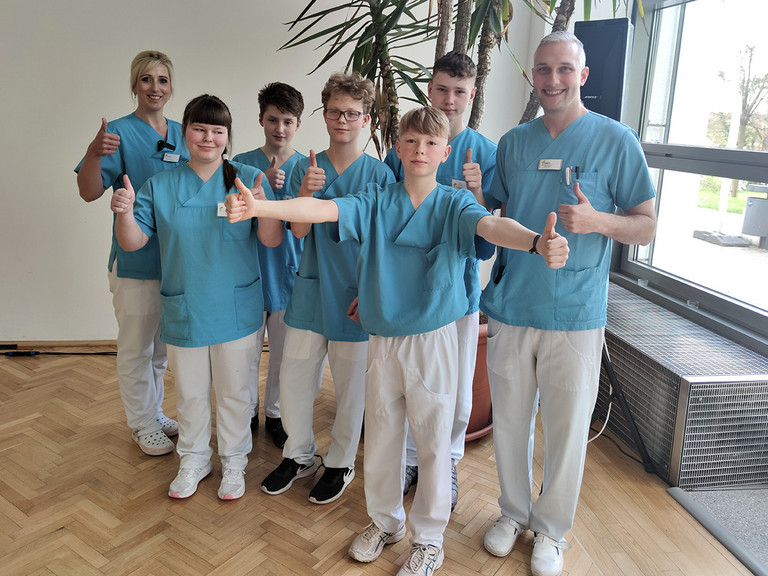 Nicole Stohf, Ausbildungsmanagerin (links), und Robert Tavernier, koordinierender Praxisanleiter (rechts), mit den Kindern des Zukunftstags Brandenburg in der Immanuel Klinik Rüdersdorf